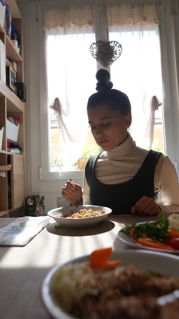 una mujer joven comiendo una comida en una mesa de comedor