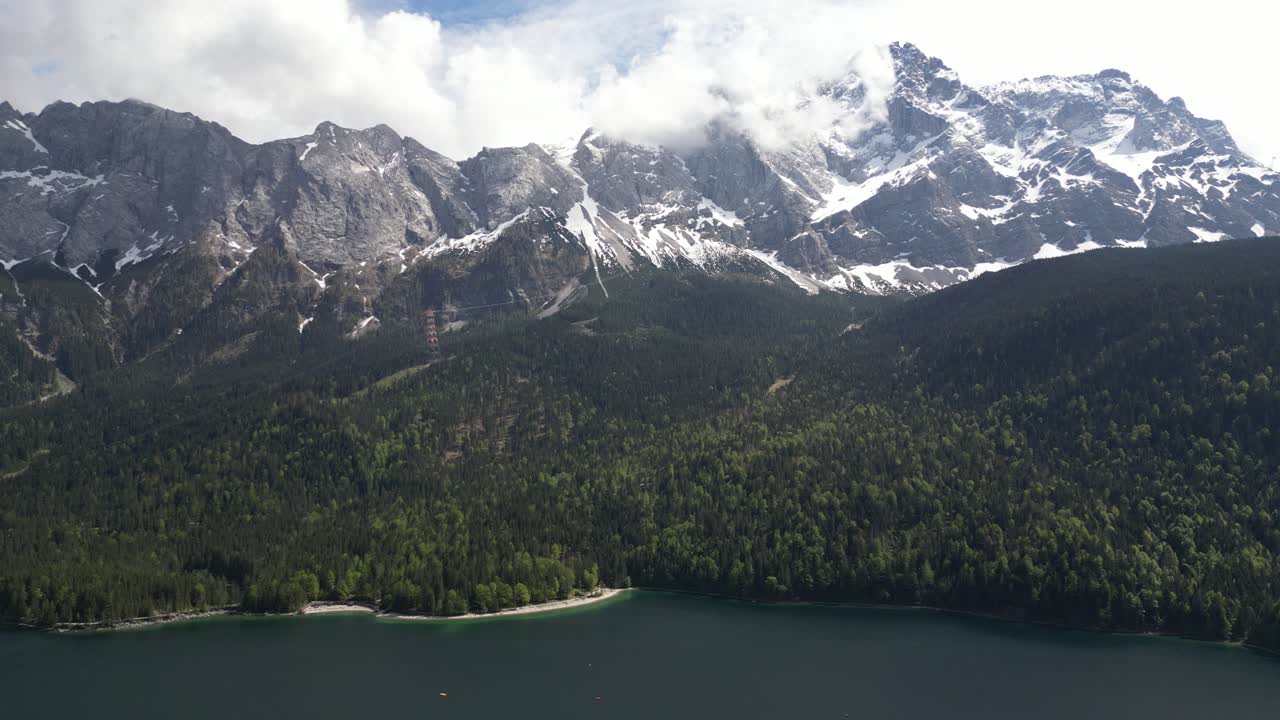 Vette montuose innevate si ergono sopra il lago Eibsee in Baviera, Germania, incarnando il concetto di maestosità naturale incontaminata e bellezza tranquilla.