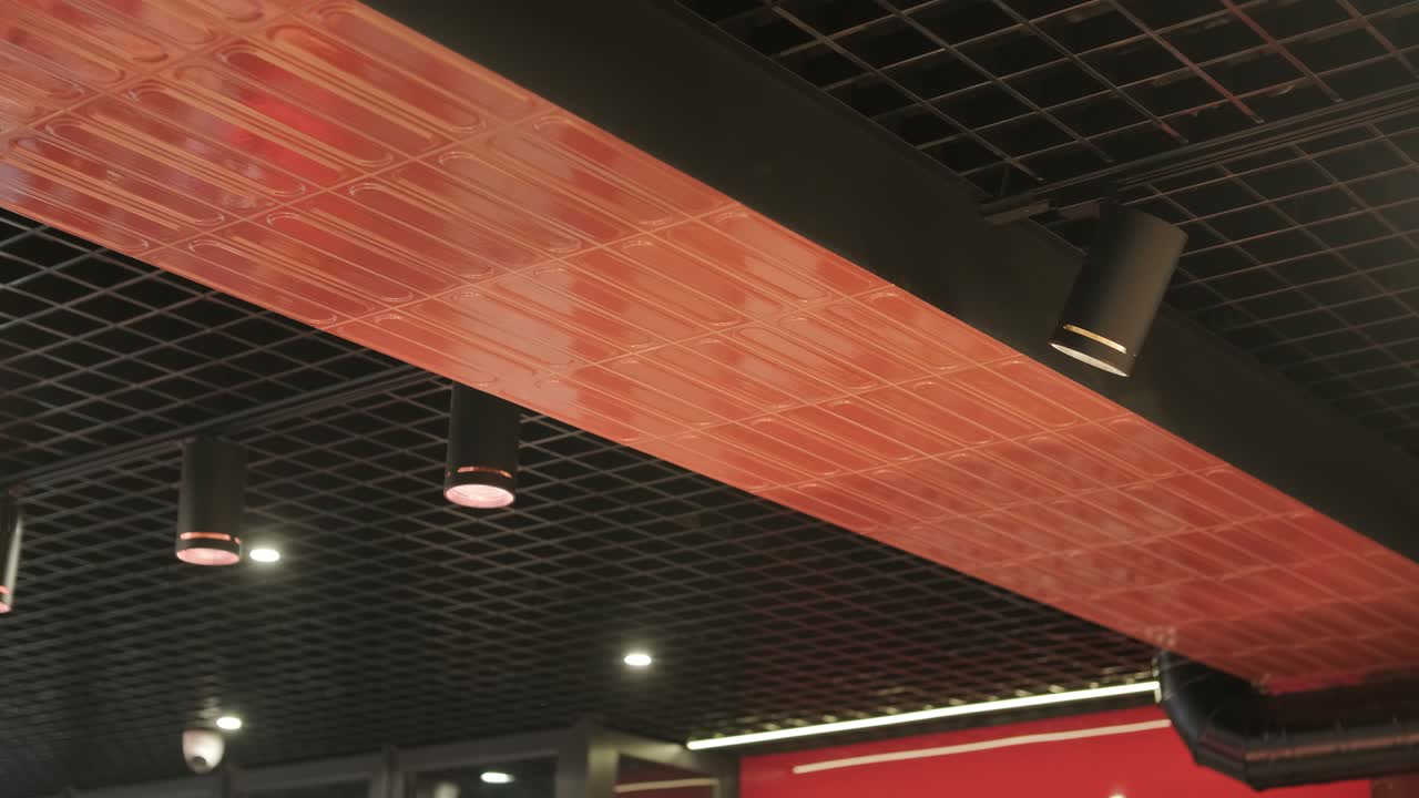 Modern ceiling featuring grid patterns, recessed lighting, pendant lamps, and a ventilation system. Sleek, contemporary design in a retail or commercial space