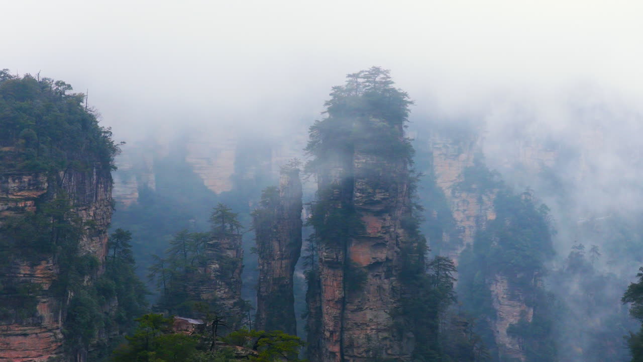 Nuvole leggere sopra gli imponenti pilastri del Parco Forestale Nazionale di Zhangjiajie in Cina. Ripresa aerea.