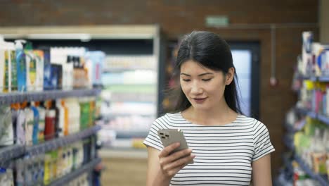 beautiful young european woman in stylish outfit with modern smartphone and many paper shopping bags using real time navigation