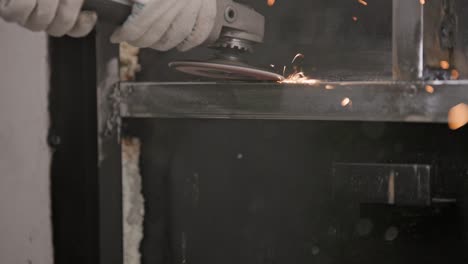 manual cleaning of welded seams with an angle grinder with a flap disc on welded metal construction close-up with long spark trails, slow motion