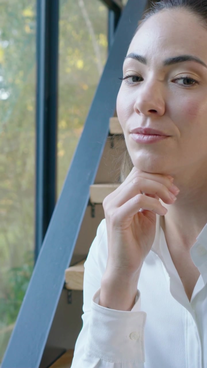 Video verticale: Donna seduta sulle scale con una sciarpa si tiene il mento, spostando lo sguardo mentre la telecamera si avvicina.