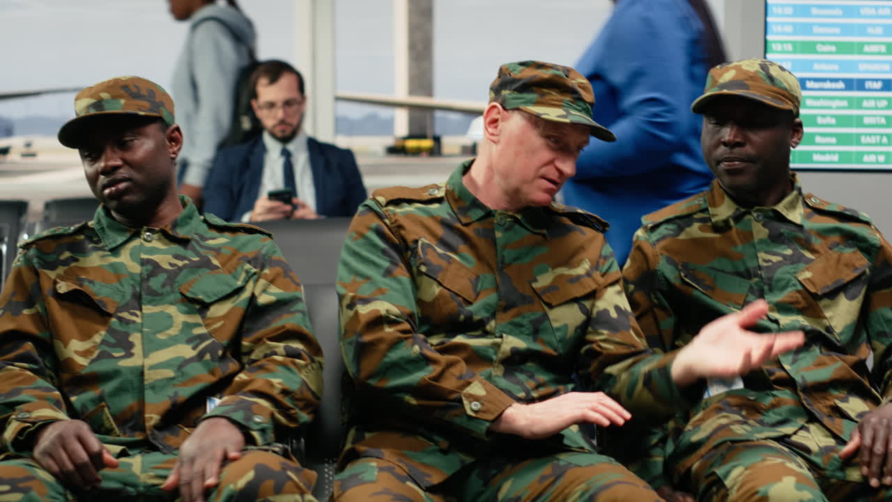 Soldati dell'esercito multietnici che chiacchierano in aeroporto, in attesa che si apra il gate d'imbarco.