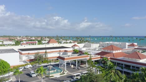 ascending aerial view of paradisus palma real resort with parking cars and beautiful caribbean sea in background