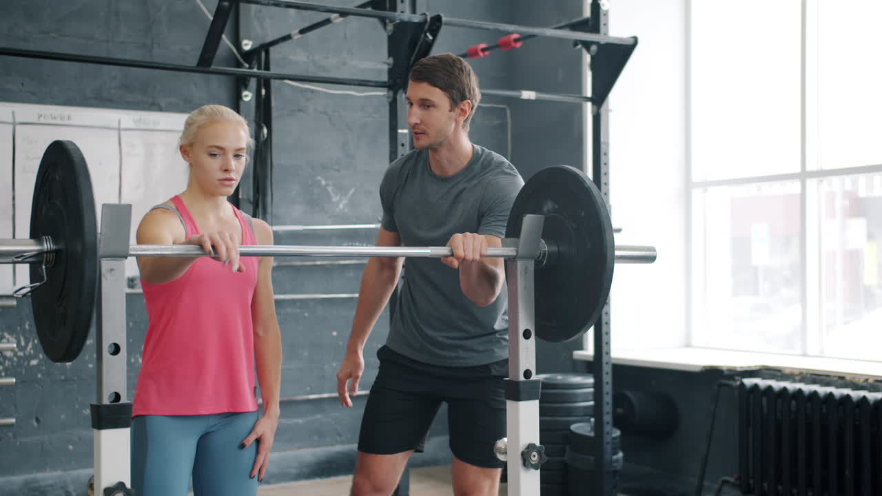 Woman lifting weights with personal trainer in gym