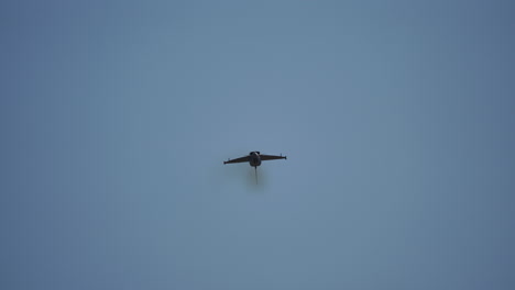 Powerful fighter jet soaring across blue sky, executing precision aerial maneuvers with stunning speed and skill during high intensity airshow performance