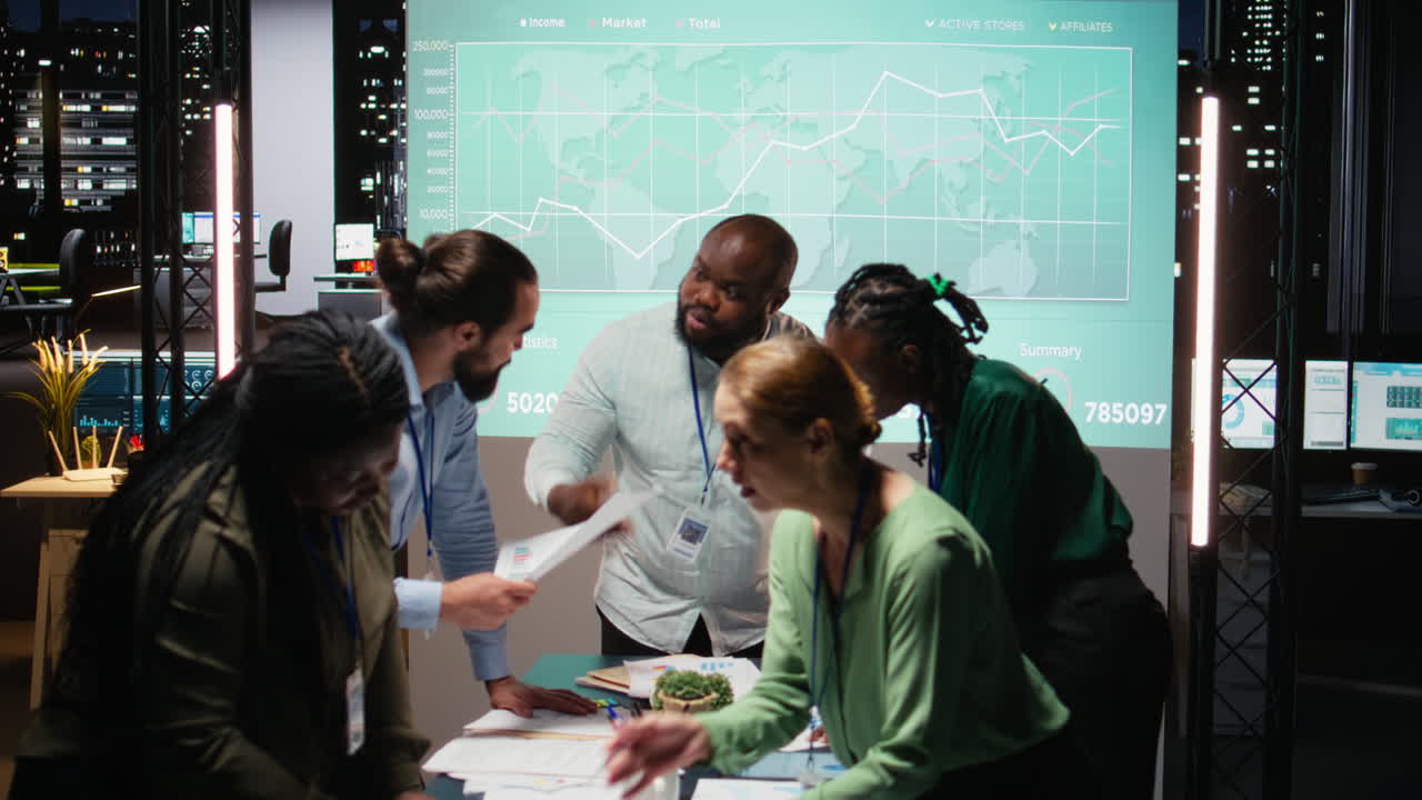 Night time meeting unfolds as a multiethnic team gathers in a strategy room