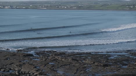 wide shot of a coastline with surfers surfing in the water