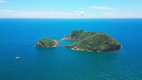 vila franca islet in sao miguel with a sailboat and clear blue waters, aerial view