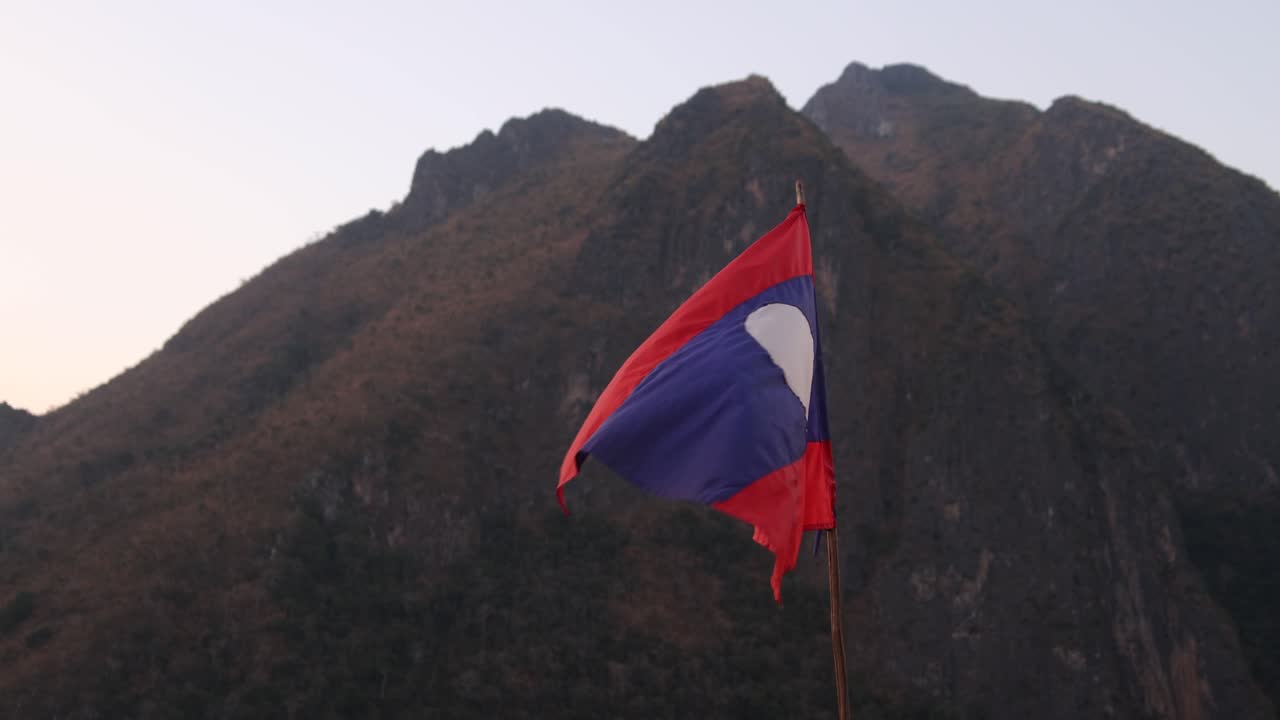 Laos flag flapping in the wind in the mountain town of Nong Khiaw in Laos, Southeast Asia