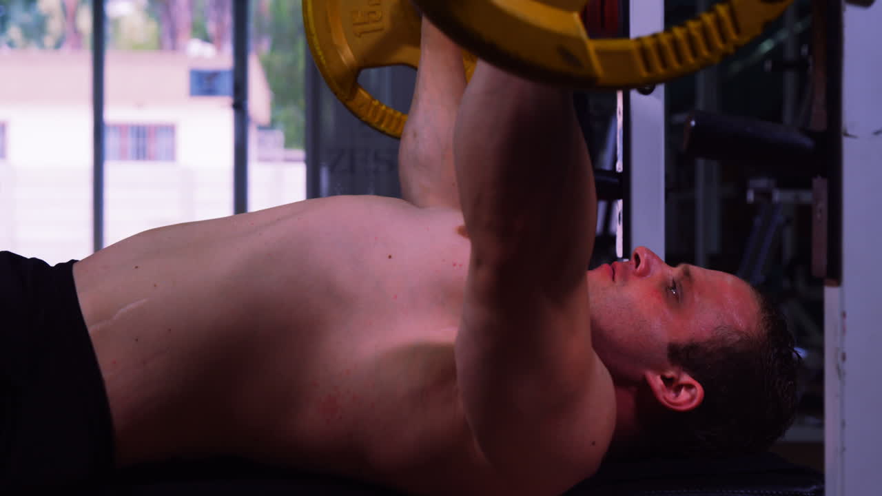 근육이 많은 남자가 바벨을 들어 올리고 있습니다.