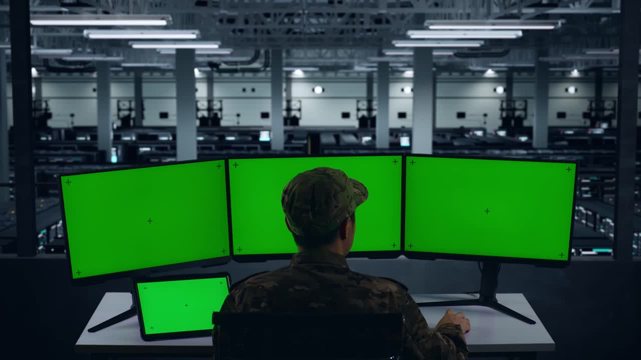 태블릿과 다중 컴퓨터 모니터로 작업하는 아시아 군대의 뒷모습 데이터 센터에서 모의 녹색 화면