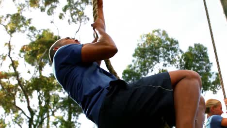 Man-climbing-the-rope-during-obstacle-course