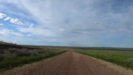 HYPER-LAPSE---Traveling-down-a-dirt-road-in-the-country-on-a-cloudy-day-with-a-blue-sky