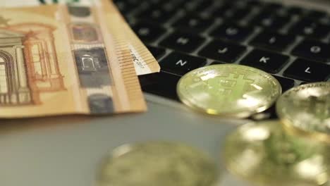 rotating close up above bitcoin coins, 50 euro paper bills, laptop in home desk office, digital versus paper currency