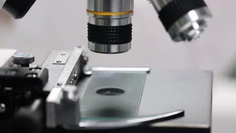 close-up of a microscope with sample slide and liquid drop in a laboratory