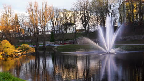 fuente escénica en el parque valmiera junto al lago dzirnavu, letonia durante la hora dorada de la luz del sol