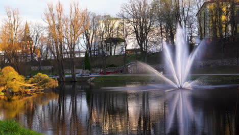 scenic fountain in valmiera park by dzirnavu lake, latvia during golden hour sunlight