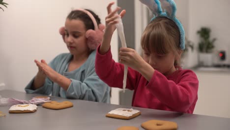 dos hermanas pequeñas decorando galletas caseras en la cocina en casa.