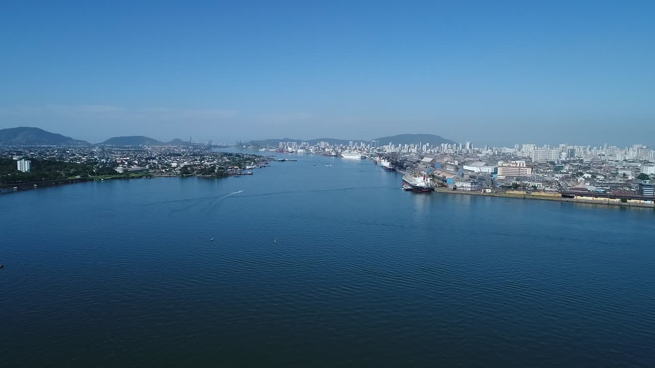 Movement ahead of Drone filming in the middle of the channel of the largest port in latin america, intense maritime trade, cargo handling, sunny blue day, immense sea