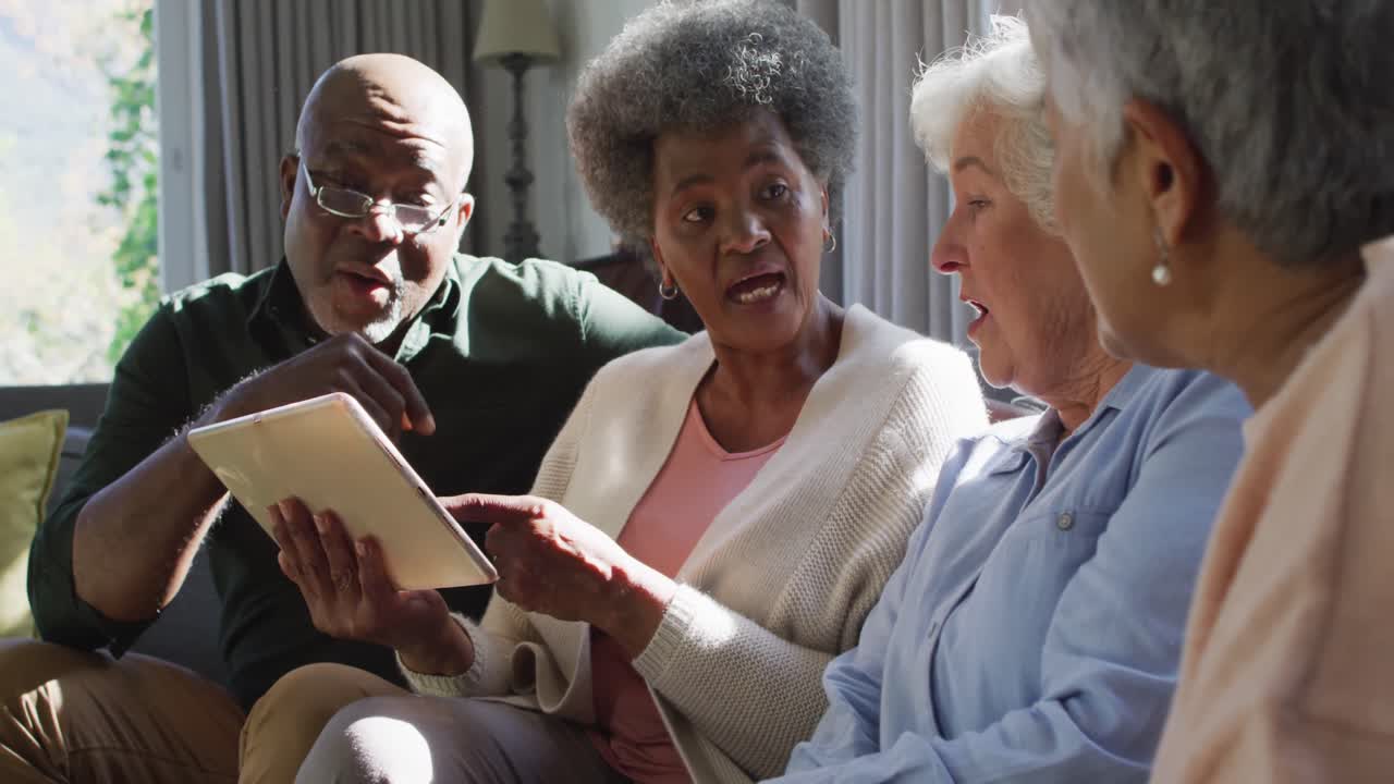 Group of diverse senior people using digital tablet together at home