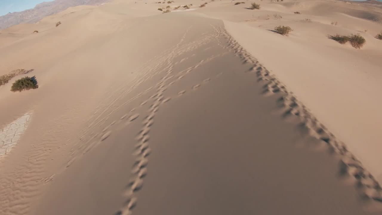 el dron se desliza rápidamente sobre el vasto paisaje desértico de marruecos, áfrica, zoomando a través de dunas de arena que se extienden sin fin, capturando los patrones ondulados y la belleza del terreno árido