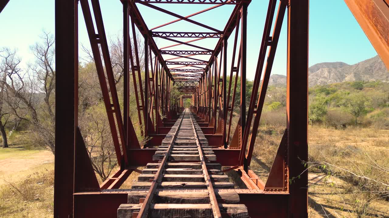 Avanzamento su un vecchio ponte ferroviario arrugginito in un paesaggio rurale
