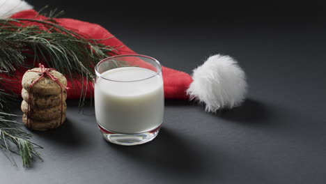 Vídeo-De-Galletas-Navideñas,-Vaso-De-Leche,-Sombrero-De-Santa-Claus-Y-Espacio-Para-Copiar-Sobre-Fondo-Negro