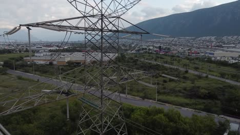 Elektrischer-Turm-Mit-Riesigen-Kabeln,-Die-Von-Einem-Ende-Zum-Anderen-Laufen.-Hochspannung-Läuft,-Wirf-Ihn-Mitten-In-Eine-Stadt-Und-Einen-Berg-Im-Hintergrund