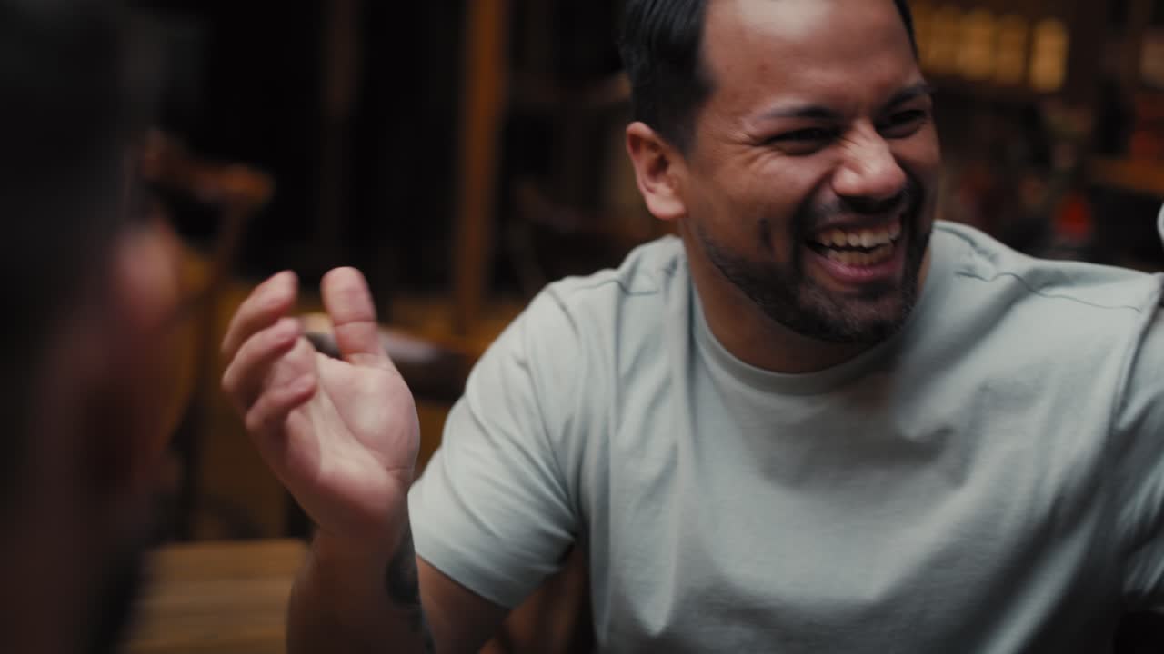 세 명의 남성 친구들이 술집에서 전화로 축구 경기를 보고 있습니다.