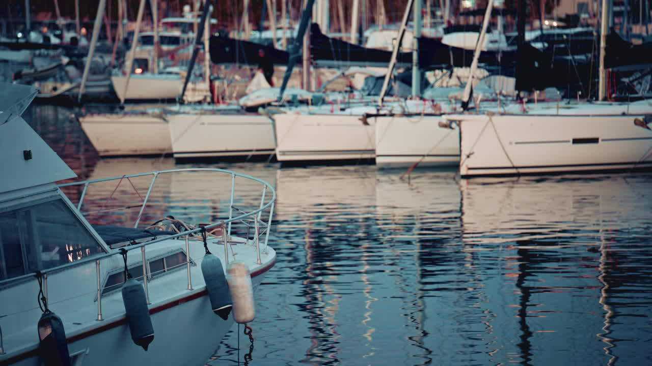 A yacht's bow in the foreground with the marina and boats in the background at blue hour
