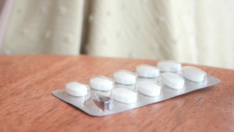 close-up of hands taking a blister pack of white pills