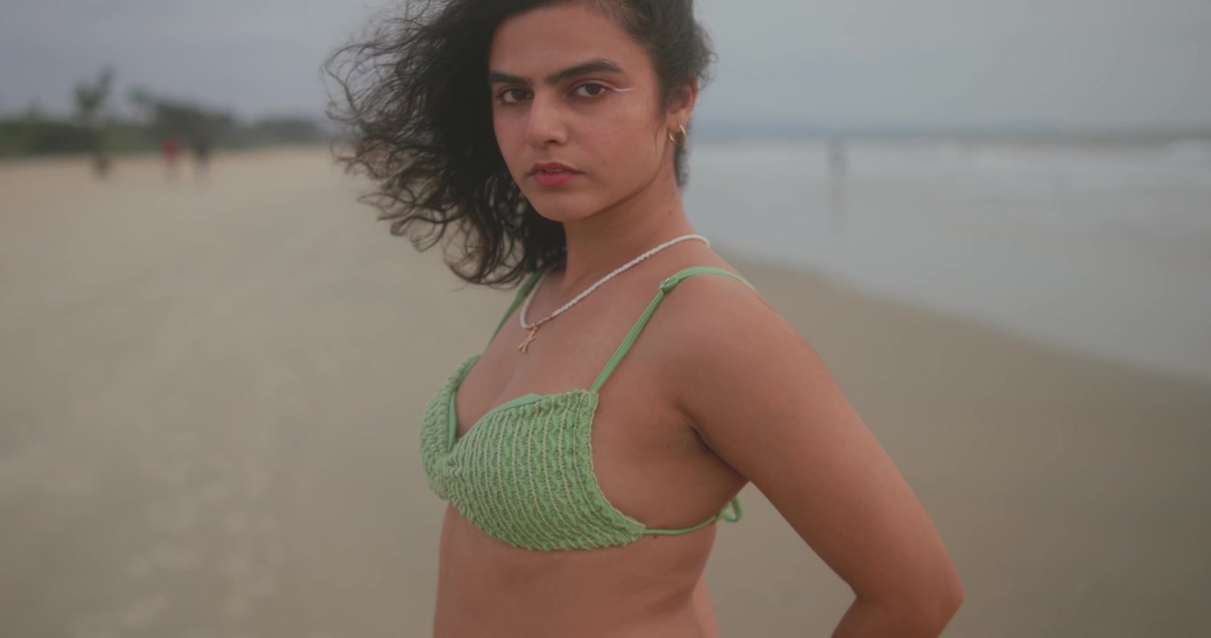 Primo piano di una giovane donna che guarda in camera su una spiaggia ventosa