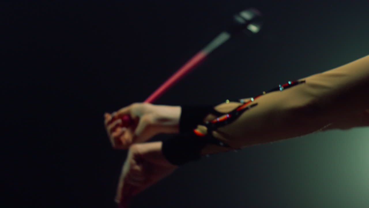 Gymnast arms twirling maces indoors. Woman hands holding sports equipment inside