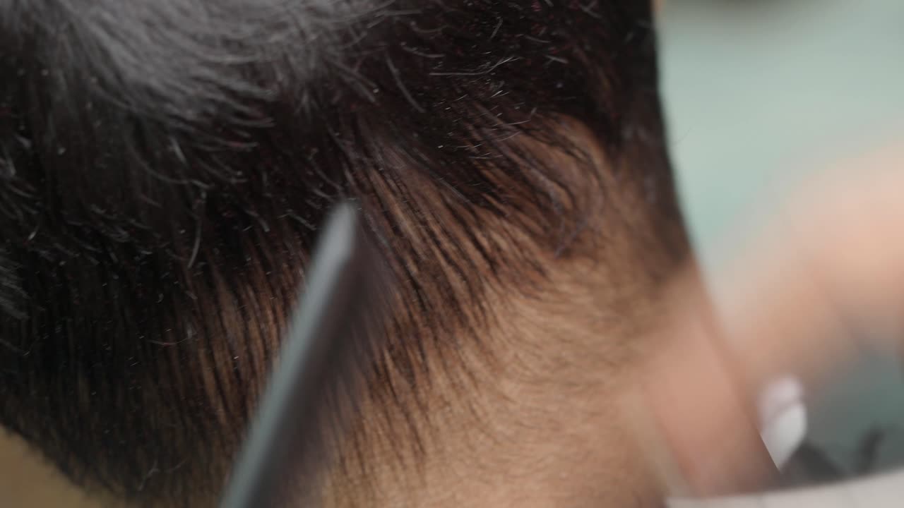 Close-up of a man's hair being cut by a barber