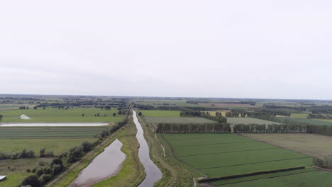 Aerial shot of a drone rising up over a flat landscape looking down a river in Cambridgeshire England.