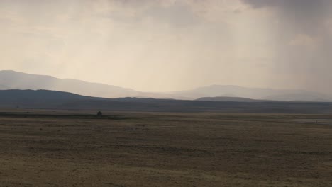 distant mountains under a hazy sky overlook a vast golden plain at sunset