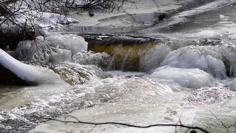 zoom en vista del río congelado cayendo sobre rocas cubiertas de hielo en cámara lenta