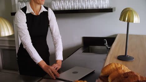 waitress walking with laptop at counter