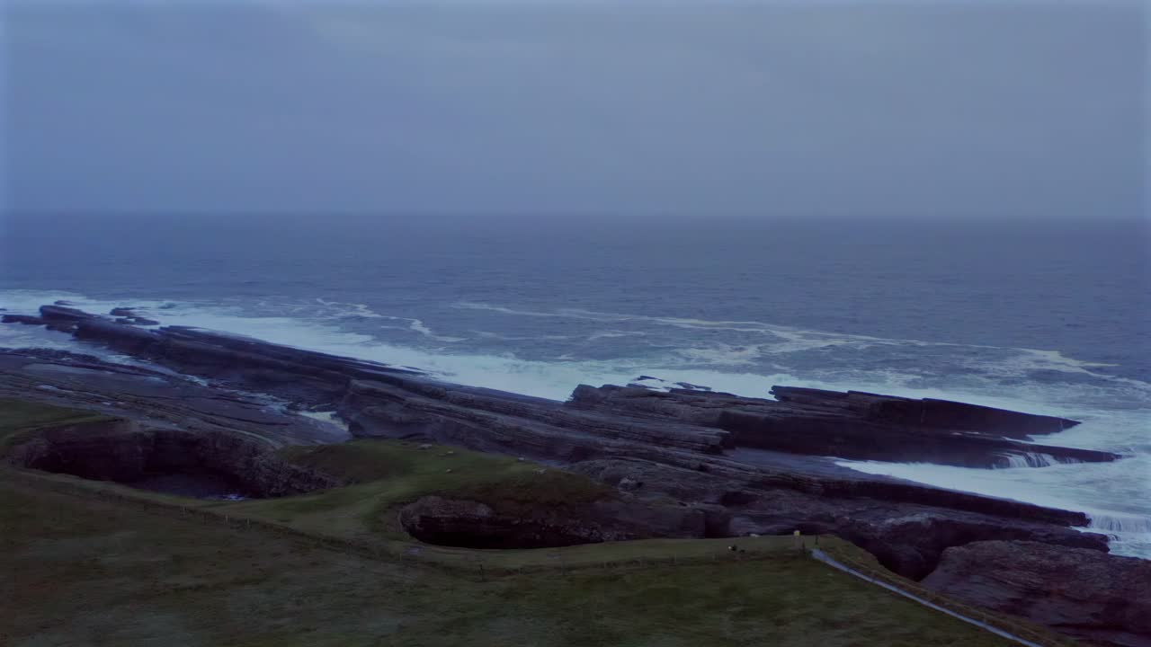 Twilight aerial orbit over the bridges of Ross, misty coastal hills, blue hour light enhances calm setting