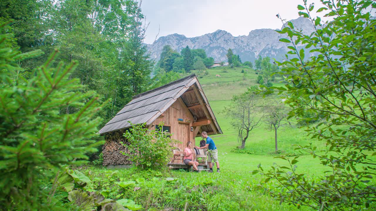 Wanderer couple near a wooden house in the forest relaxing and having a drink