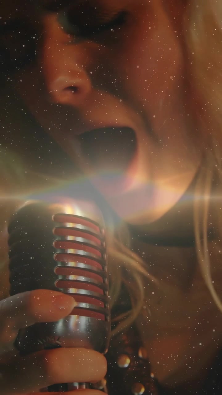 Video verticale: Cantante donna che inizia a cantare, afferrando il microfono per la musica, con un bagliore che attraversa la griglia e stelle.