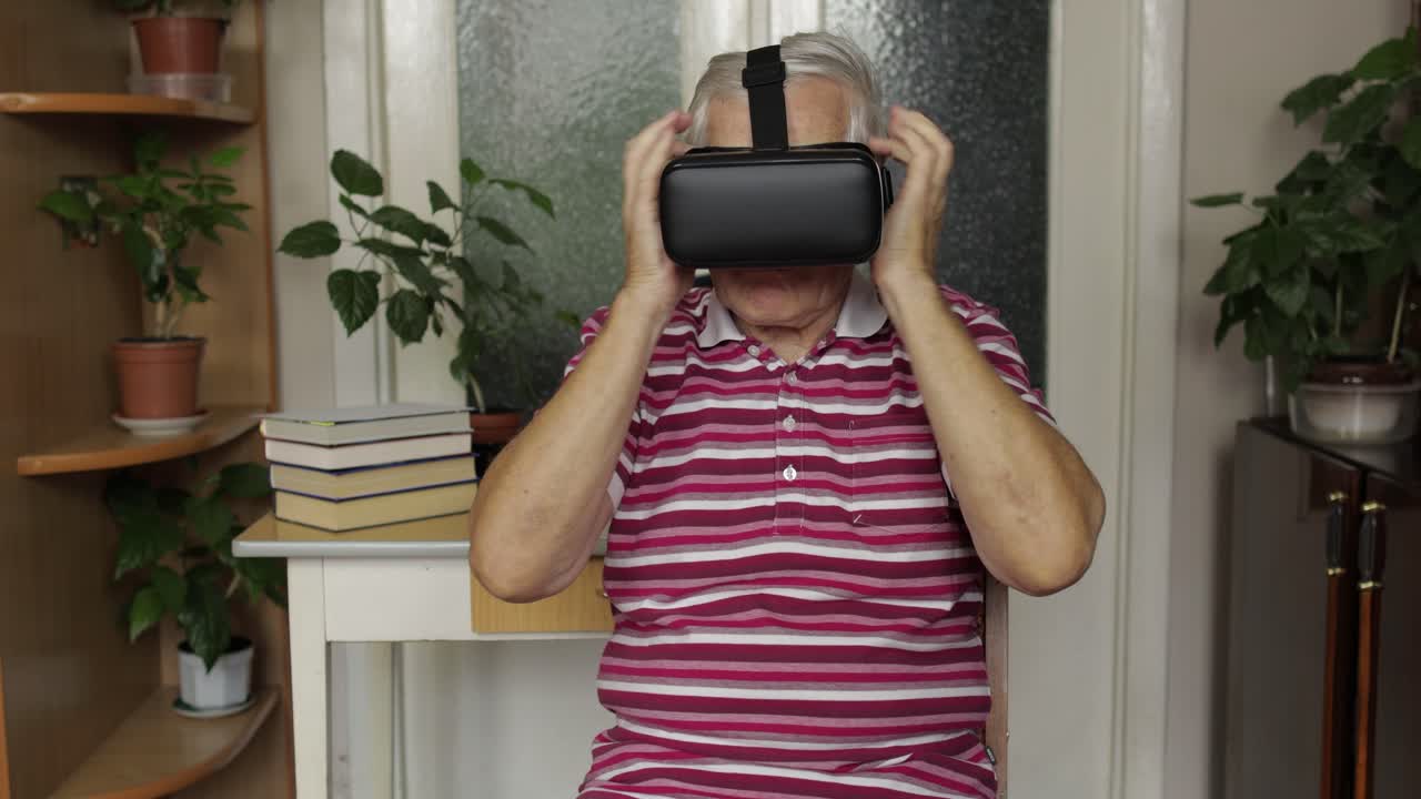 Senior grandfather putting on virtual headset glasses and watching 3d video in 360 vr helmet at home