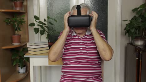 senior grandfather putting on virtual headset glasses and watching 3d video in 360 vr helmet at home