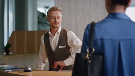 receptionist assisting hotel guests at desk closeup. tourist couple make payment