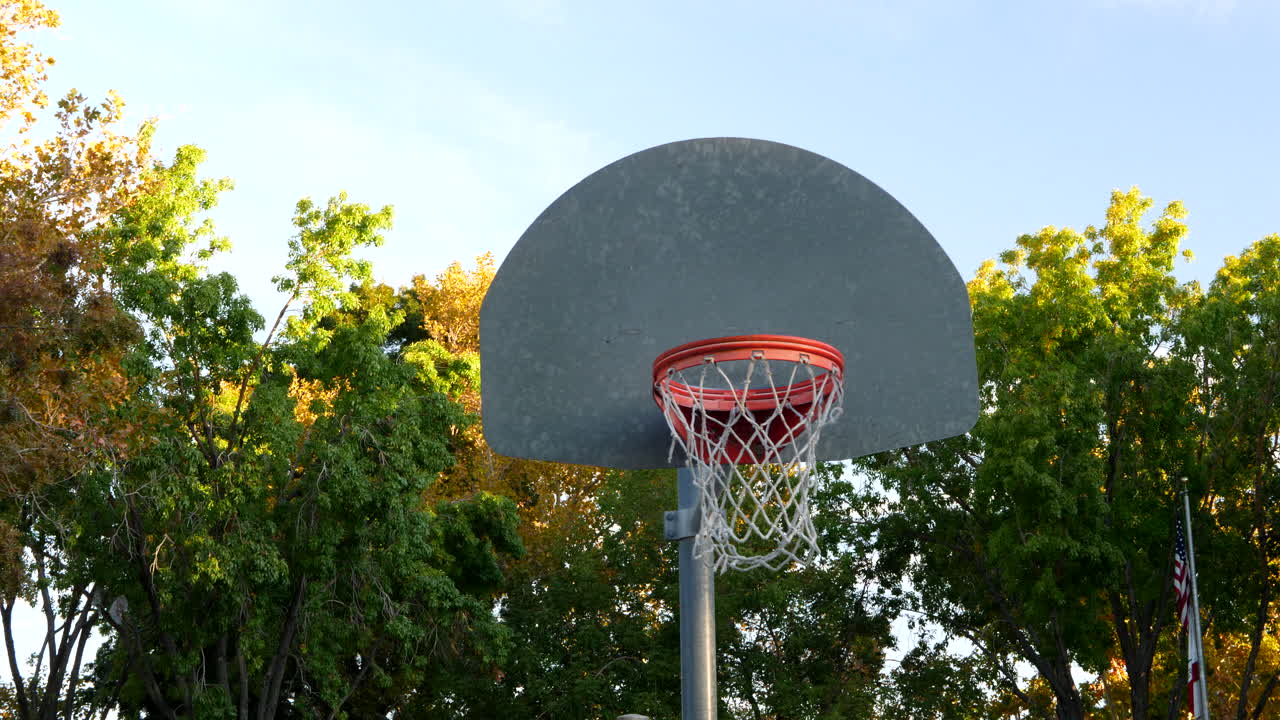 일출 시 빈 공원 코트에서 금속 백보드와 주황색 테두리가 있는 농구 후프의 오른쪽 샷을 슬라이드합니다.