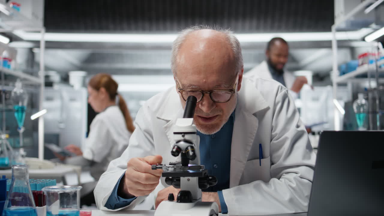 Biólogo sênior sorrindo em laboratório médico usando microscópio científico