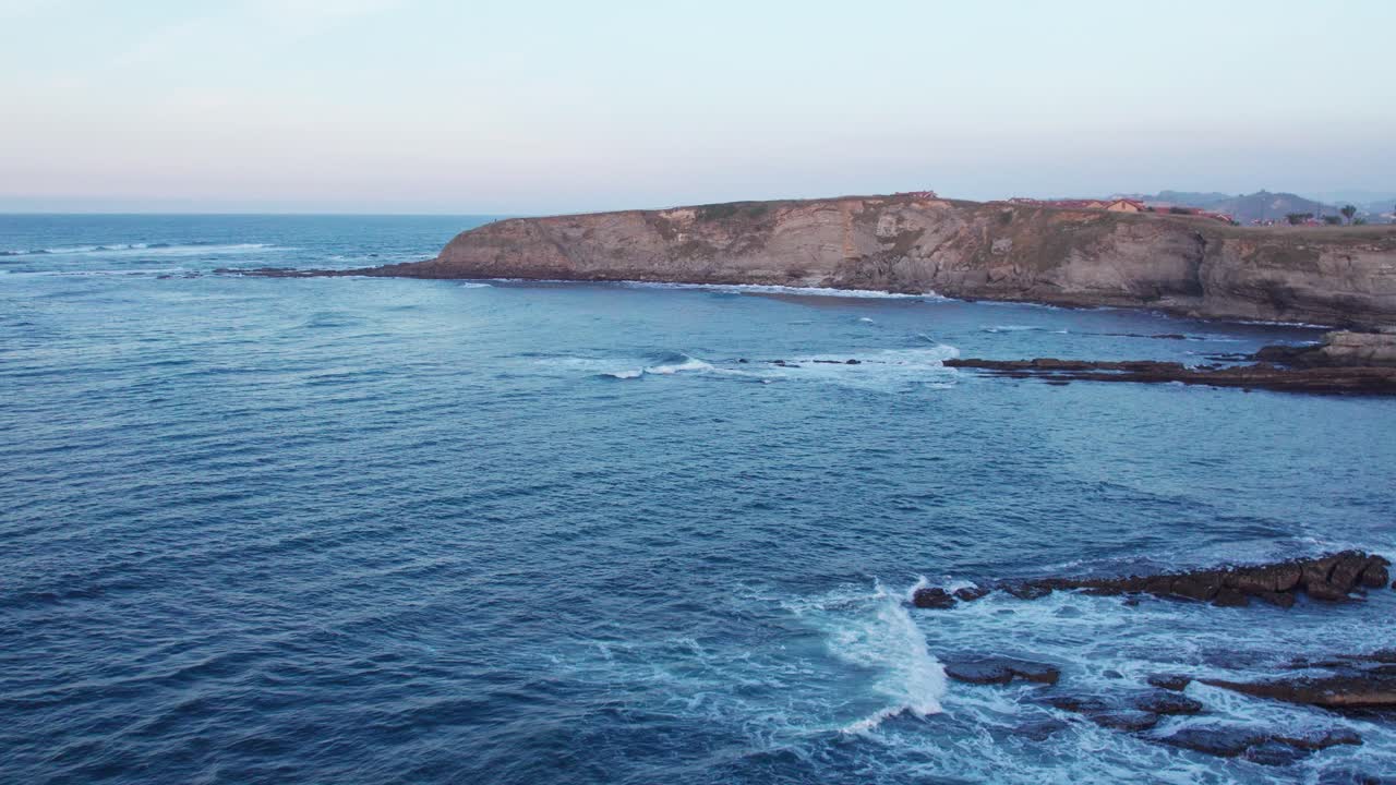 drone volando hacia una colina rocosa rodeada de azul