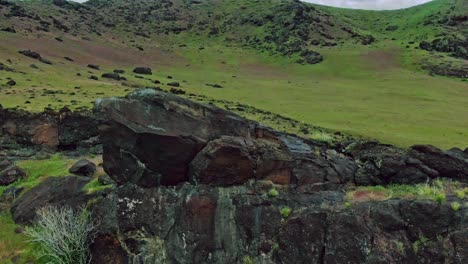 Orbit-Around-Black-Rocky-Green-Hills-with-Bird-Flyby-Aerial-Drone-Footage-Fast-on-Cloudy-Day-near-Old-Path-and-Interstate-15-in-Central-Utah-USA